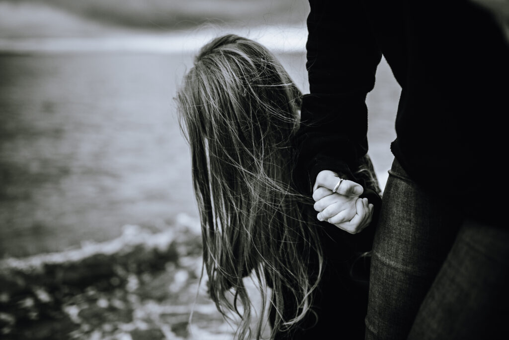 Black and white photo of a woman holding a childs hand, standing next to the ocean shoreline. Tiffany Dawn, web design consultation Vancouver Island — Paper & Pine Creative.